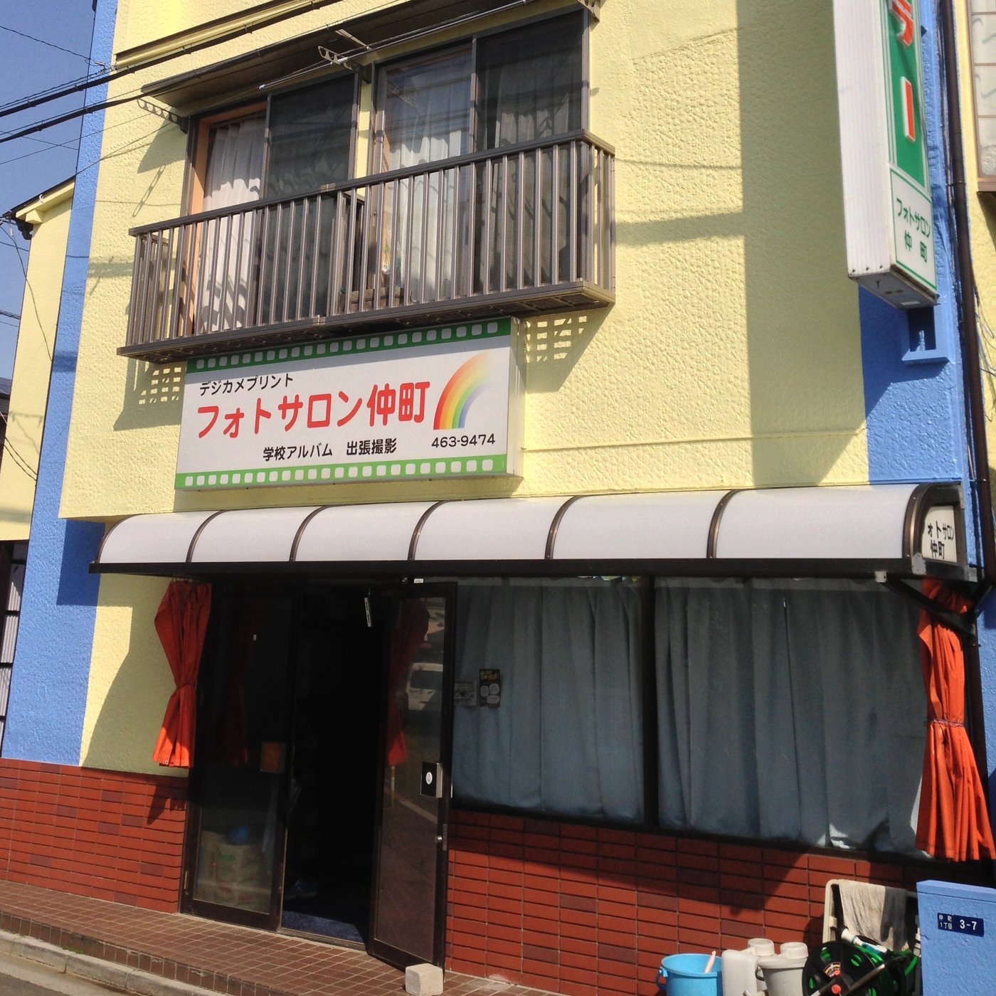 フォトサロン仲町の入口。看板に「デジカメプリント フォトサロン仲町 学校アルバム 出張撮影 463-9474」